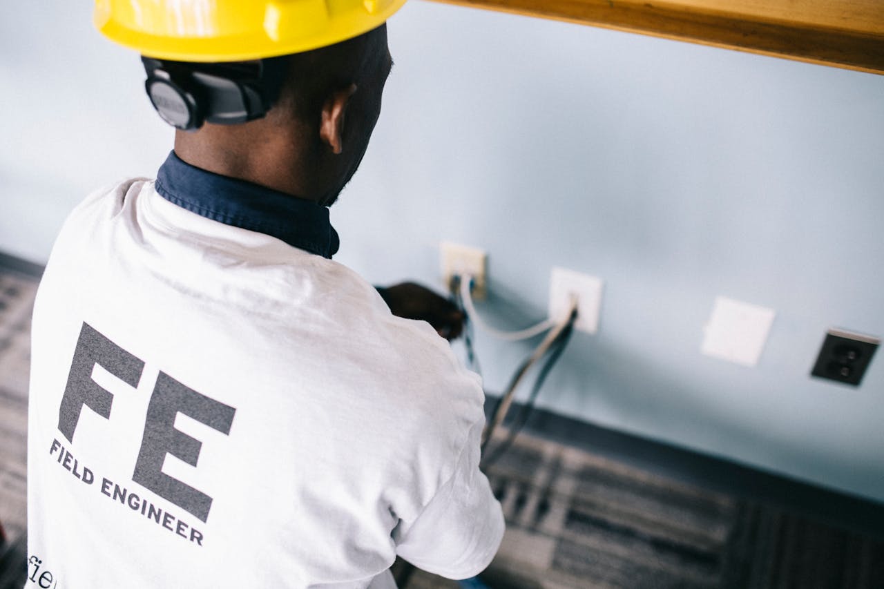 The Art of Drawing Readers In: Your attractive post title goes here From above back view unrecognizable black field engineer wearing white shirt and protective hardhat sitting on floor and checking voltage in wall plugs